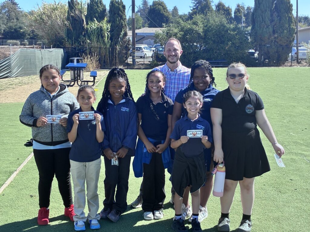 Andrew Grossman smiles in a photo with seven Caliber students.