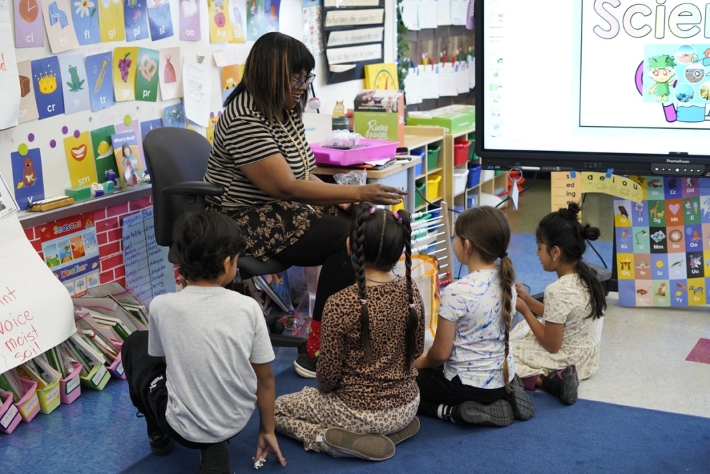 Astrid Howard Taylor Smiles As She Sits With A Group Of Students