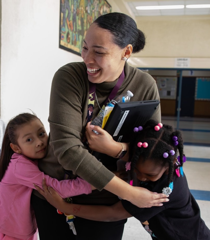 Educator Hugging Students At School