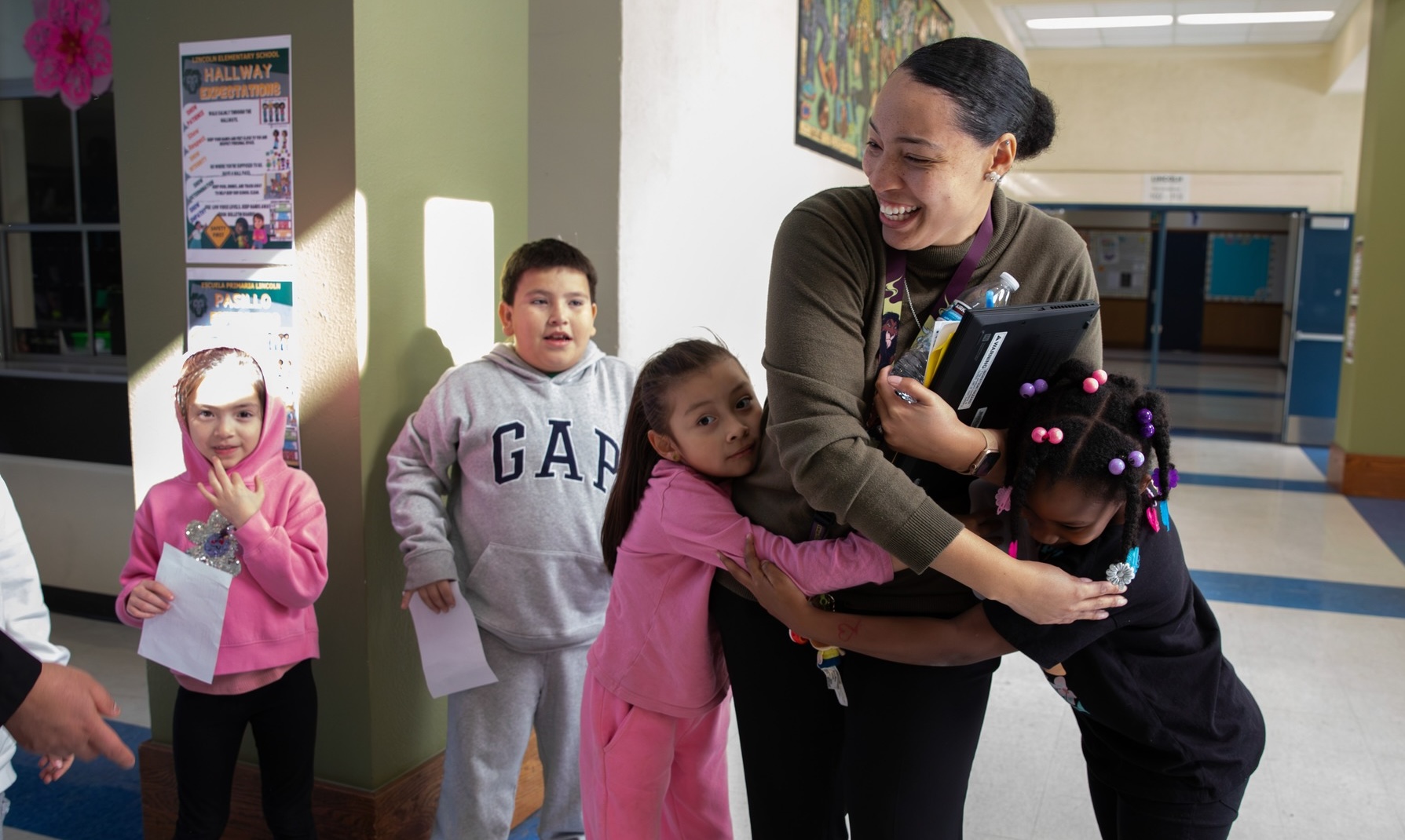 Educator Hugging Students In Hallway