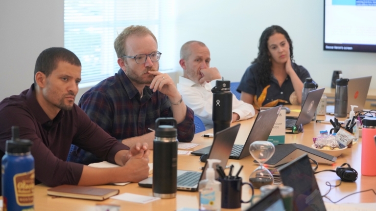 Michael Burks se sienta a la mesa con otros durante una reunión de líderes docentes.