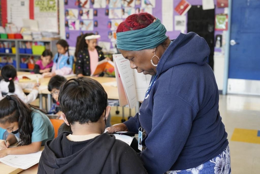 Veronica Adams Leans Over As She Works With A Student