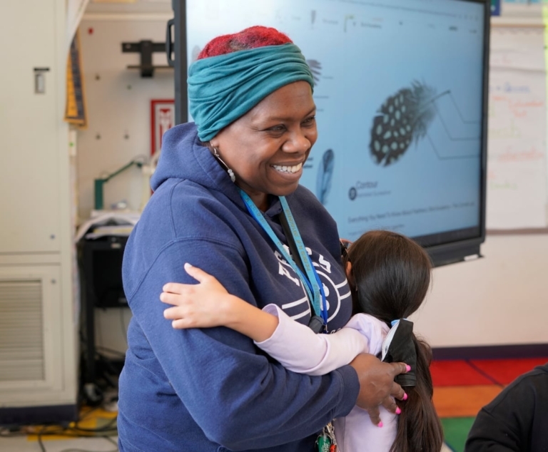 Veronica Adams Smiles As She Holds A Student